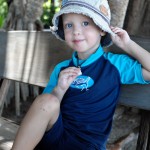 Max håller i mössan och visar sitt nya geckohalsband